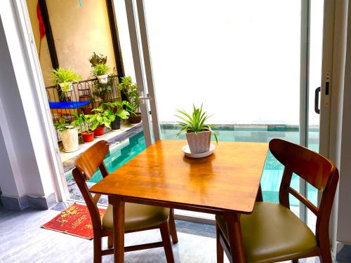 a wooden table and chairs in a room with potted plants at An Bang Sea Adventure Homestay Hoi An in Hoi An