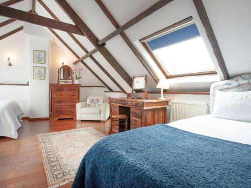 a bedroom with a bed and a desk and a window at The Barn in Kentisbeare