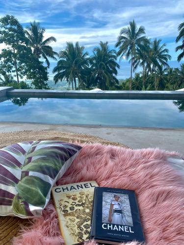 a book and pillows on a blanket on a beach at Bintana sa Paraiso Binunsaran in Mambajao