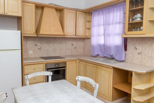 una cocina con armarios de madera y una mesa con sillas. en Depis economy apartments, en Naxos Chora