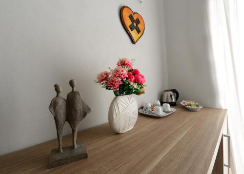 una mesa con un jarrón de flores y una estatua de dos personas en Dimora del Cuore struttura self check in en Vieste