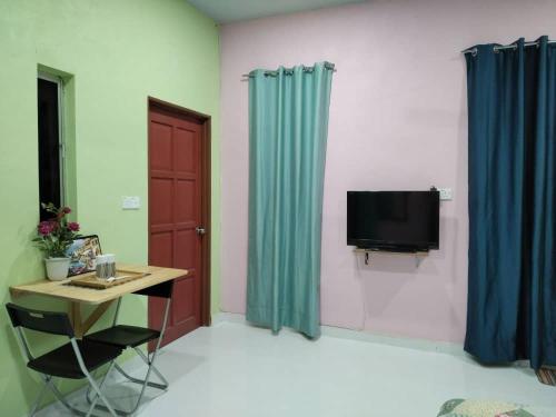 een kamer met een bureau, een televisie en blauwe gordijnen bij Inap Desa 1 