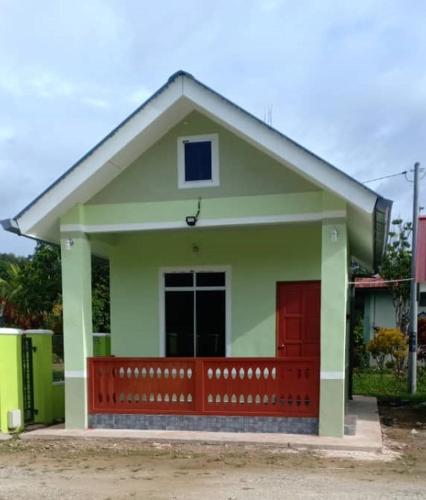 een klein groen en rood huis met een rode deur bij Inap Desa 1 