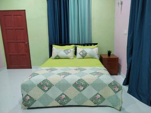 een bed met een groene dekbed en kussens in een slaapkamer bij Inap Desa 1 