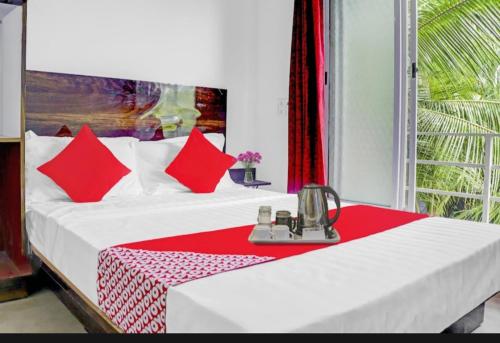 a bed with red pillows in a room with a window at Sea Nest in Alibaug
