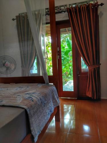 a bedroom with a bed and a sliding glass door at Sumatra Orangutan Discovery Villa in Bukit Lawang