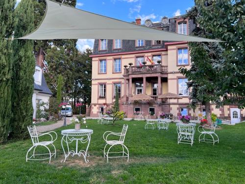 eine Gruppe von Stühlen und Tischen vor einem Gebäude in der Unterkunft Hôtel Le Manoir in Barr