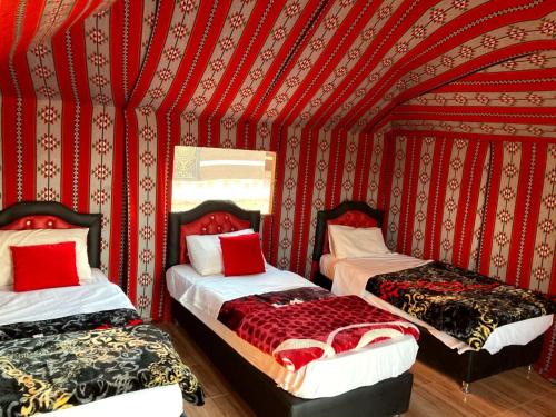 two beds in a room with a red wall at Wadi Rum in Wadi Rum
