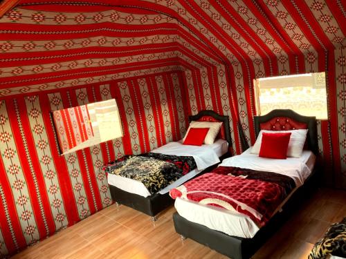 two beds in a room with a red wall at Wadi Rum in Wadi Rum
