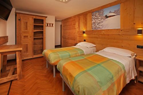 two beds in a room with wooden walls at Hotel Biancaneve in Sauze dʼOulx