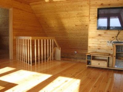 a room with a wooden wall with a window and a television at Kalnakriknas in Dzimtmisa