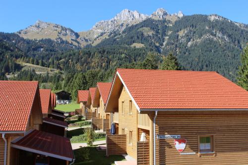 a row of wooden houses with mountains in the background at Feriendorf am Hahnenkamm in Reutte