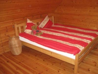 a bed in a wooden room with a red and white blanket at Kalnakriknas in Dzimtmisa