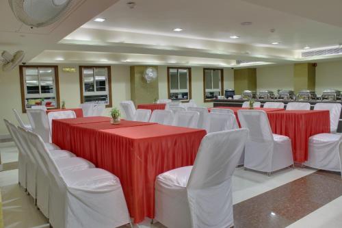 a conference room with red and white tables and white chairs at The Royal Melange Beacon in Ajmer