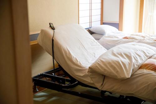 two beds in a room with white sheets at Matsusaki in Nomi