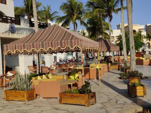 an outdoor patio with tables and chairs and palm trees at Hawana Salalah Laguna Studio in Salalah