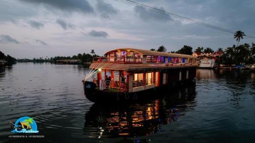 a boat in the water with a house on it at Vaishnav Tours in Alleppey
