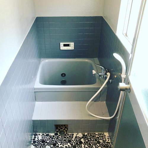 a bath tub in a bathroom with blue tiles at 洲本家　SUMOTOYA in Sumoto