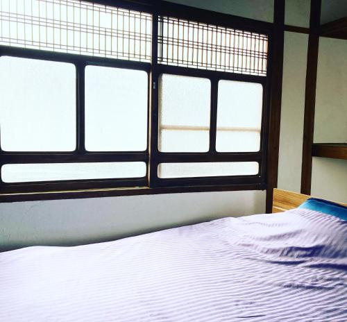 a bedroom with four windows and a white bed at 洲本家　SUMOTOYA in Sumoto