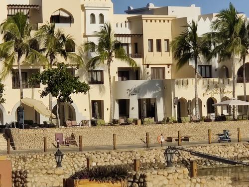 a large building with palm trees in front of it at Hawana Salalah Laguna Studio in Salalah