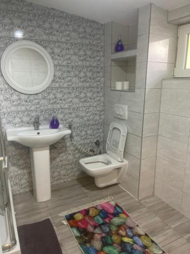 a bathroom with a sink and a toilet and a mirror at Apartman Maki in Sarajevo