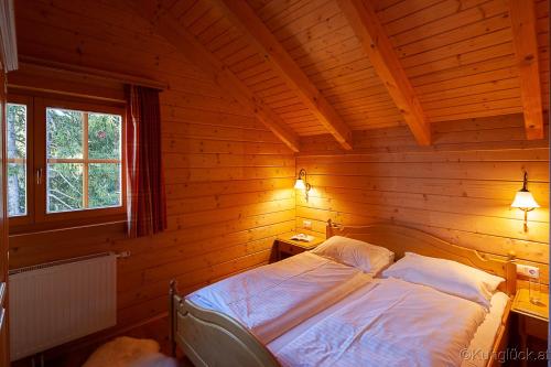 ein Schlafzimmer mit einem Bett in einer Holzhütte in der Unterkunft Kuhglück Koralpe in Elsenbrunn