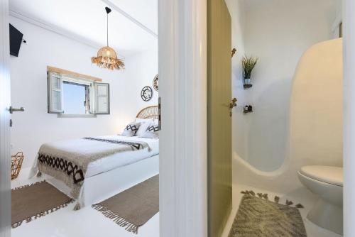 a white bedroom with a bed and a bathroom at Parian Philoxenia Villa, Santa Maria Beach in Kampos Paros