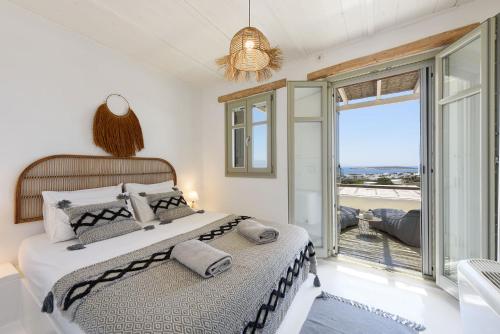 a bedroom with a bed and a large window at Parian Philoxenia Villa, Santa Maria Beach in Kampos Paros