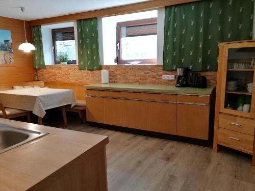 cocina con cortinas verdes, mesa y encimera en Berghof Knabl, en Arzl im Pitztal