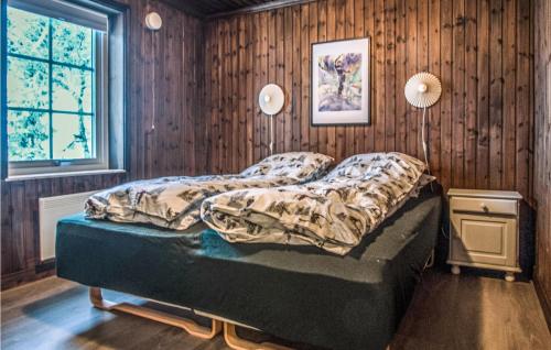 a bed in a bedroom with a wooden wall at Lovely Home In Trysil With Wifi in Trysil