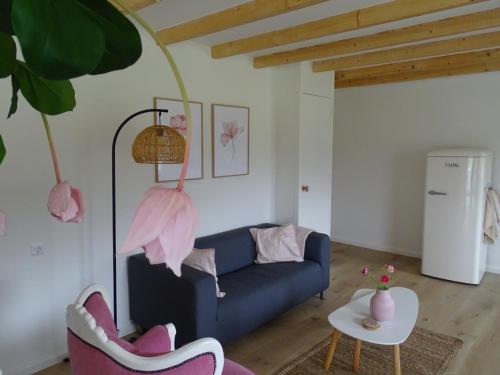 sala de estar con sofá azul y sillas rosas en de Tulp, en Noordgouwe