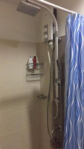 y baño con ducha y cortina azul. en Eagle's Nest - Furnished 1BR Condo w/ WIFI en Manila