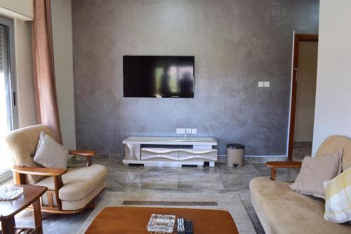 een woonkamer met een bank en een tv aan de muur bij Baron Palace hotel suites in Aqaba