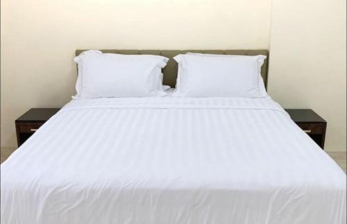a white bed with two pillows on top of it at CENTRAL JAKARTA HOMESTAY FAST WIFI in Jakarta