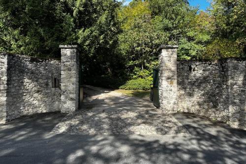 an entrance to a stone wall with a gate at Spacious house in a wooded park enclosed by walls and its swimming pool in Saint-Cyr-sur-Loire