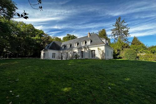 duży biały dom na zielonym polu w obiekcie Spacious house in a wooded park enclosed by walls and its swimming pool w mieście Saint-Cyr-sur-Loire