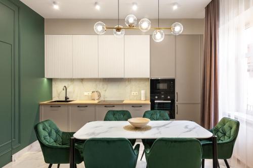 リヴィウにあるLEOGRAND VIP Apartments on Lesi Ukrainky 7のキッチン(テーブル、緑の椅子付)