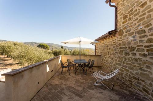 a patio with a table and chairs and an umbrella at Antico Casale Tiravento in Passignano sul Trasimeno