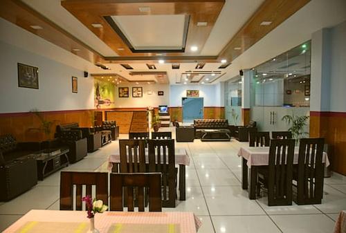 a dining room with tables and chairs in a restaurant at Jai Hotel By Boho in Pālampur