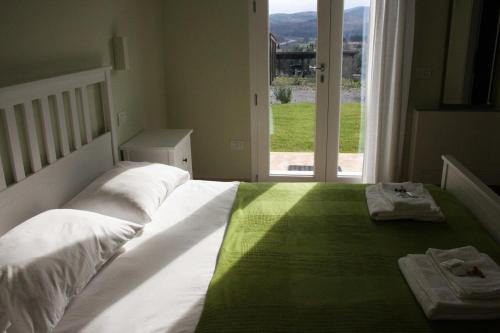 a white bed with a green blanket and a window at Poggiobono Country House in Marsiliana