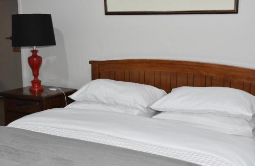 a bed with white sheets and a red lamp on a table at The Rise BNB - Executive Ensuite in Auckland