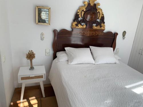 a bed with a wooden headboard and a clock on the wall at Es Forn - Cadaqués in Cadaqués