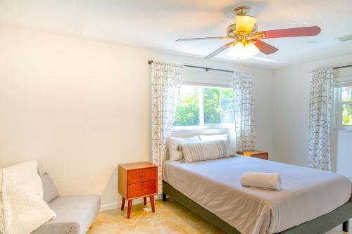 a bedroom with a bed with a ceiling fan and a chair at Pompano Treasure in Pompano Beach
