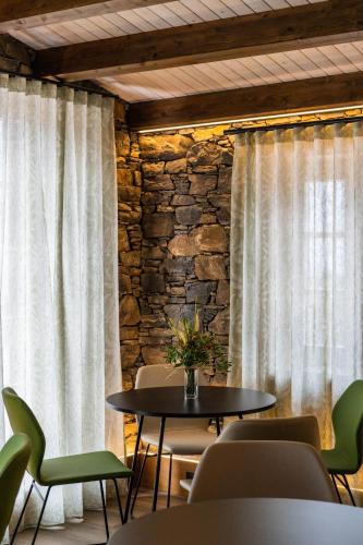 a room with a table and chairs and a stone wall at Casa Rural San Andrés de Teixido in Cedeira