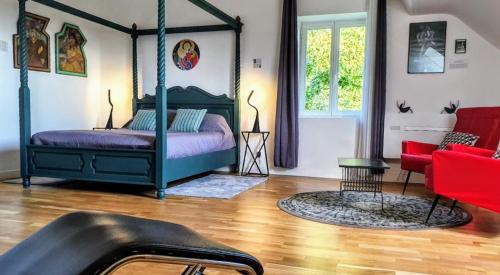 sypialnia z łóżkiem z baldachimem i czerwonymi krzesłami w obiekcie Les Hauts de Domme - Chambres d'hôtes w mieście Domme