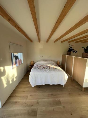 a bedroom with a bed in a room with wooden ceilings at de Tulp in Noordgouwe