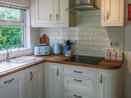 a kitchen with white cabinets and a sink and a window at The Seaside Cottage in Gorleston-on-Sea