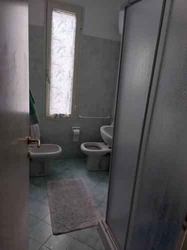 een badkamer met 2 toiletten en een raam bij Casa Fiorita in Rosignano Solvay