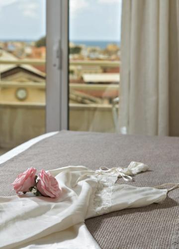 a white dress on a bed with two pink roses at Kydon The Heart City Hotel in Chania Town