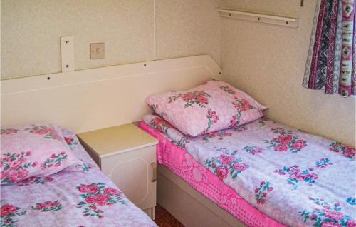 ダルウォボにあるAwesome Caravan In Darlowo With 2 Bedroomsのピンクのシーツが備わる小さな部屋のベッド2台